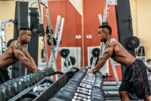 Muscular man exercising with dumbbells in gym, emphasizing strength and fitness.
