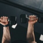 a man lifting two dumbs in a gym